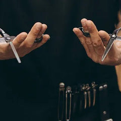 Professional barber holds two balanced grooming shears for precision and comfort.