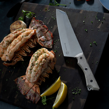 Razor Sharp AZ Messermeister Overland 8-inch chef knife with canvas Micarta handle next to cooked lobster tails.