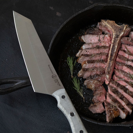 Razor Sharp AZ Messermeister Overland Chef 8-inch camp knife with canvas Micarta handle slicing steak in a cast iron pan