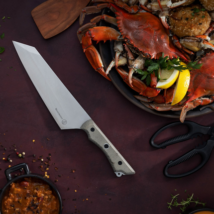 Razor Sharp AZ Messermeister Overland 8-inch chef camp knife with a canvas Micarta handle next to a plate of crab.