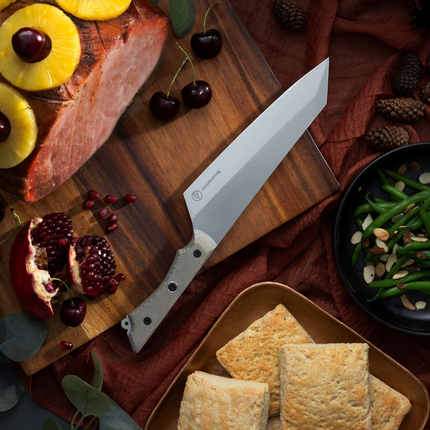 Razor Sharp AZ 8-inch Overland Chef camp knife with a canvas Micarta handle on a wooden cutting board with food.