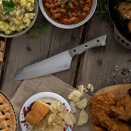 Razor Sharp AZ Messermeister Overland 8-inch chef knife with a green canvas Micarta handle on a rustic wooden table.