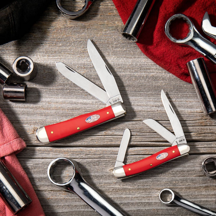 Razor Sharp AZ Case American Workman red synthetic trapper knives with carbon steel blades on a rustic wooden surface