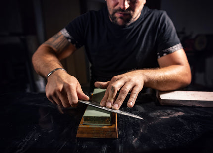 Razor Sharp AZ blade sharpening service: man meticulously sharpening a knife on a whetstone.