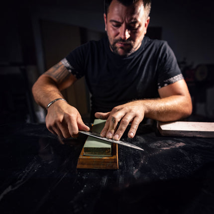 Razor Sharp AZ blade sharpening service: man meticulously sharpening a knife on a whetstone.