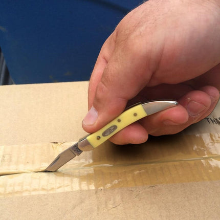 Razor Sharp AZ Case Small Texas Toothpick knife with a yellow synthetic handle cutting through cardboard tape