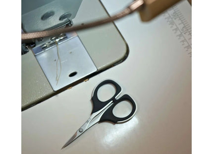 Razor Sharp AZ KAI 7100 4-inch detail scissors with black elastomer handles and high carbon stainless steel blades on a sewing machine.