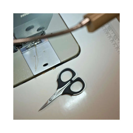 Razor Sharp AZ KAI 7100 4-inch professional stainless steel scissors with black elastomer handles on sewing machine