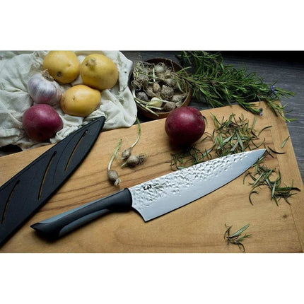 Razor Sharp AZ Kai Luna 8" chef's knife with hammered steel blade and ergonomic handle, next to potatoes, garlic, and rosemary.