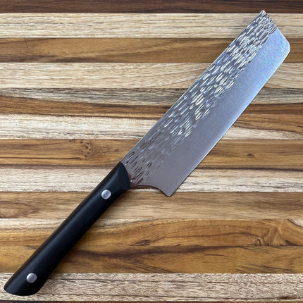 Razor Sharp AZ Kai Pro 6" Nakiri knife with hammered stainless steel blade and black POM handle on a wooden cutting board.