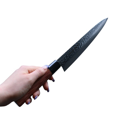 Razor Sharp AZ Kanetsune Gyuto chef knife with a hammered tsuchime finish and wooden handle held in a hand.