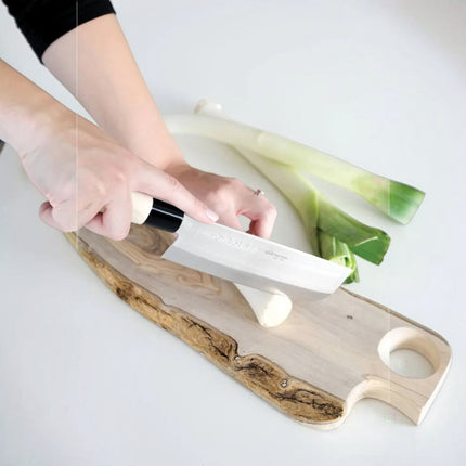 Razor Sharp AZ Due Cigni Nakiri knife with maple wood handle slicing leeks on a wooden cutting board.