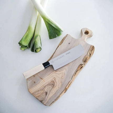 Razor Sharp AZ Due Cigni Nakiri knife with maple wood handle on a rustic cutting board with leeks.
