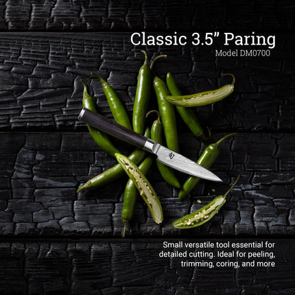 Razor Sharp AZ Shun Classic 3.5-inch paring knife with Damascus steel blade and ebony handle on charred wood with chilis