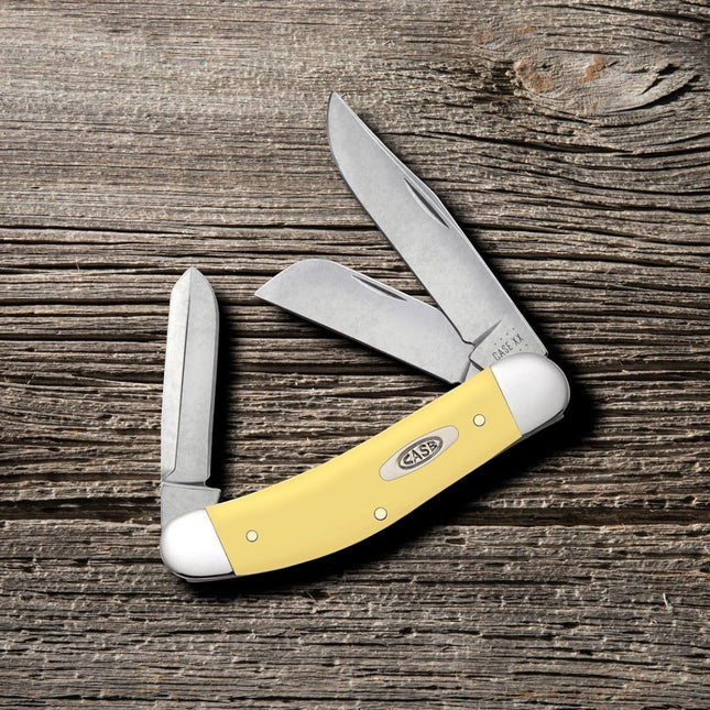 Razor Sharp AZ Yellow Synthetic CS Sowbelly pocket knife with three carbon steel blades on a rustic wood background.